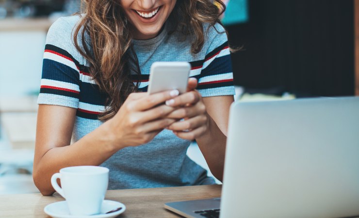 donna sorridente con smartphone in mano