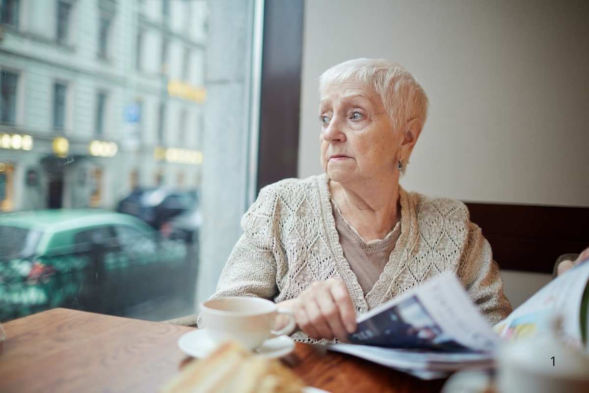 donna anziana triste guarda fuori da vetrina