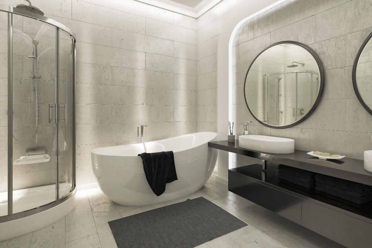 Stanza da bagno toni bianco e grigio, con vasca, grande specchio rotondo, lavabo