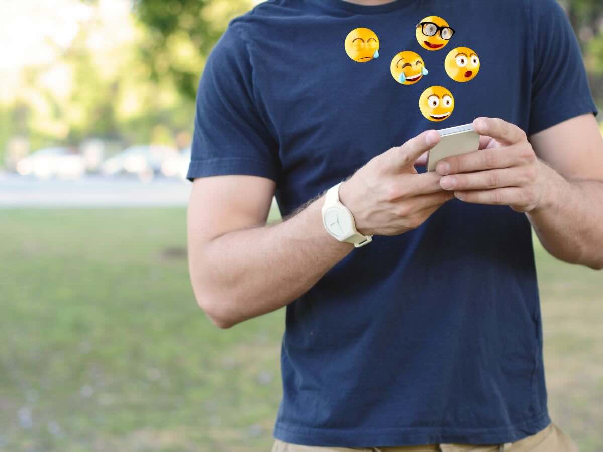 Ragazzo con smartphone e varie emoticon che escono da esso