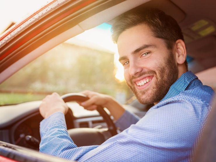 uomo sorridente alla guida di un'auto